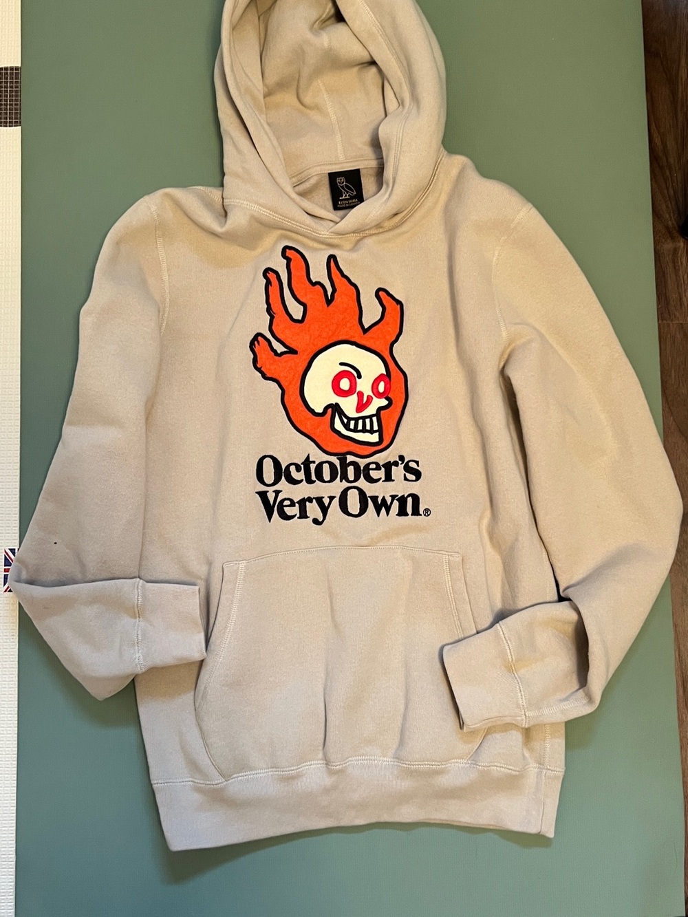 OVO Beige Crewneck Hoodie with Orange Flame Skull Graphic